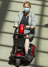 Woman, masked riding on mobility scooter at Dartmouth-Hitchcock Medical Center